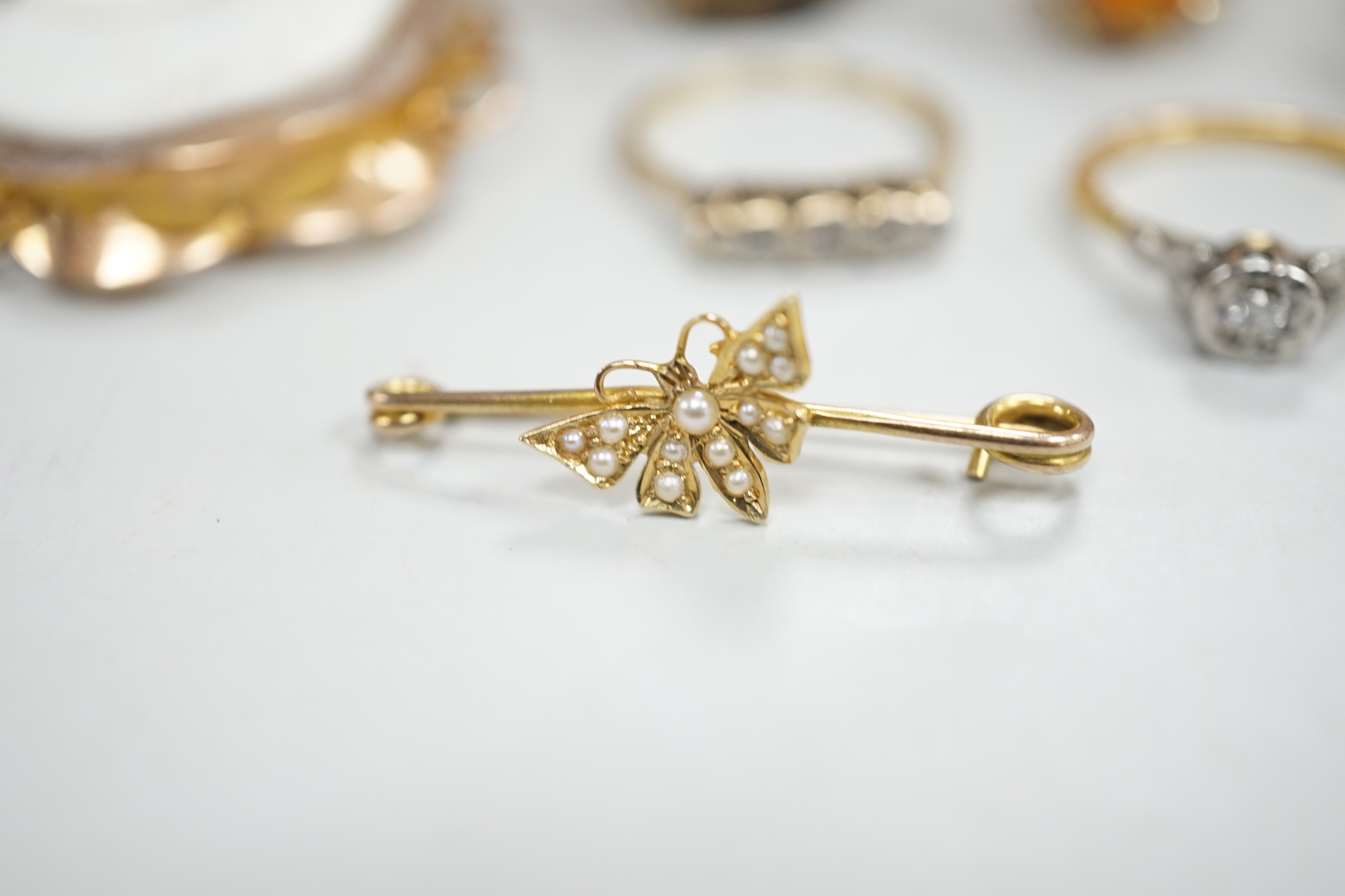 Two yellow metal and illusion set diamond rings, two 9ct gold and gem set rings, two yellow metal and gem set rings and two brooches, including 9ct mounted cameo shell.